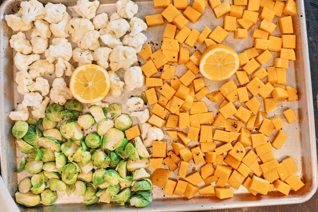 Fall Cous Cous butternut squash, cauliflower, brussel sprouts and lemon on a baking sheet