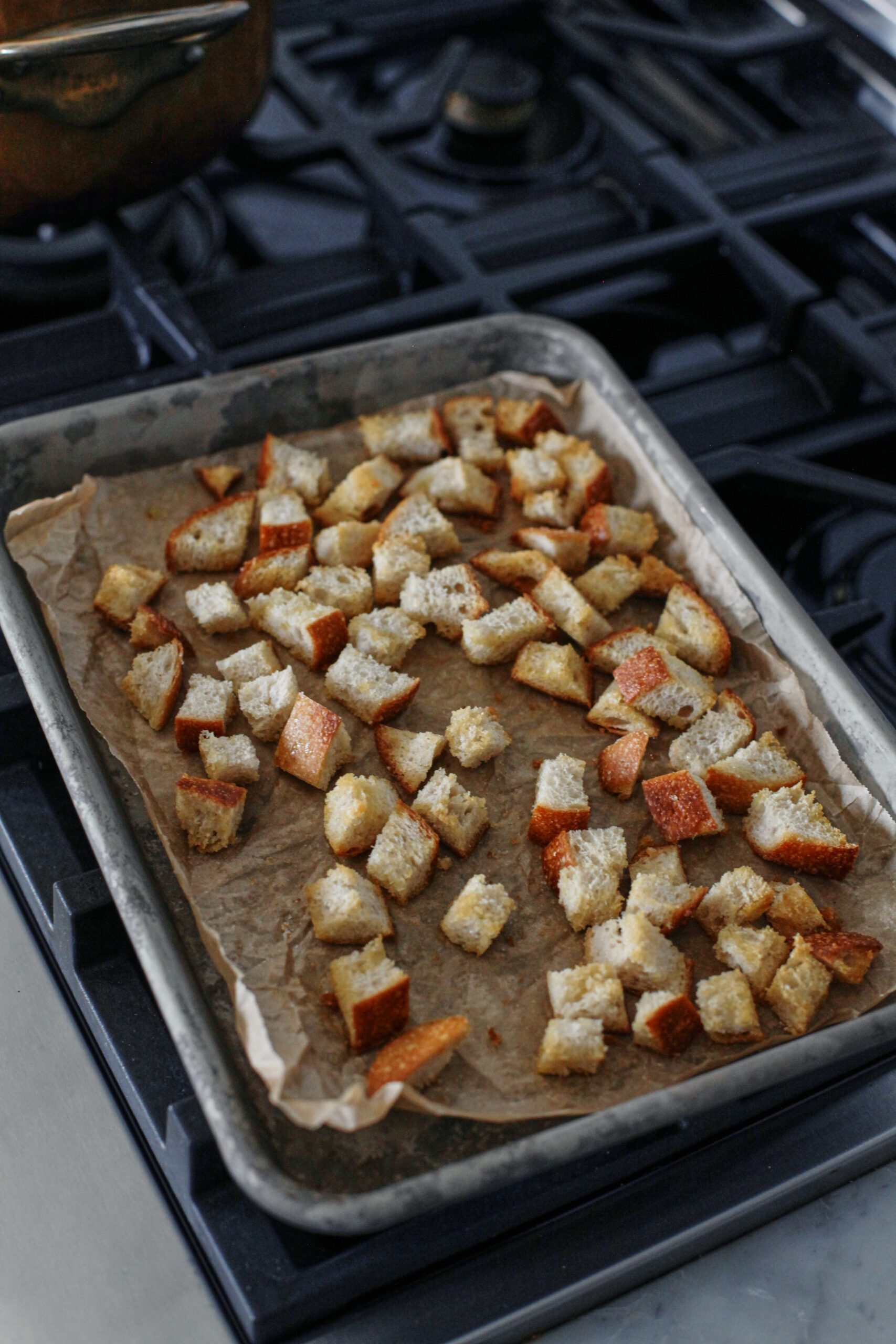 croutons toasting on a parchment-lined sheet pan
