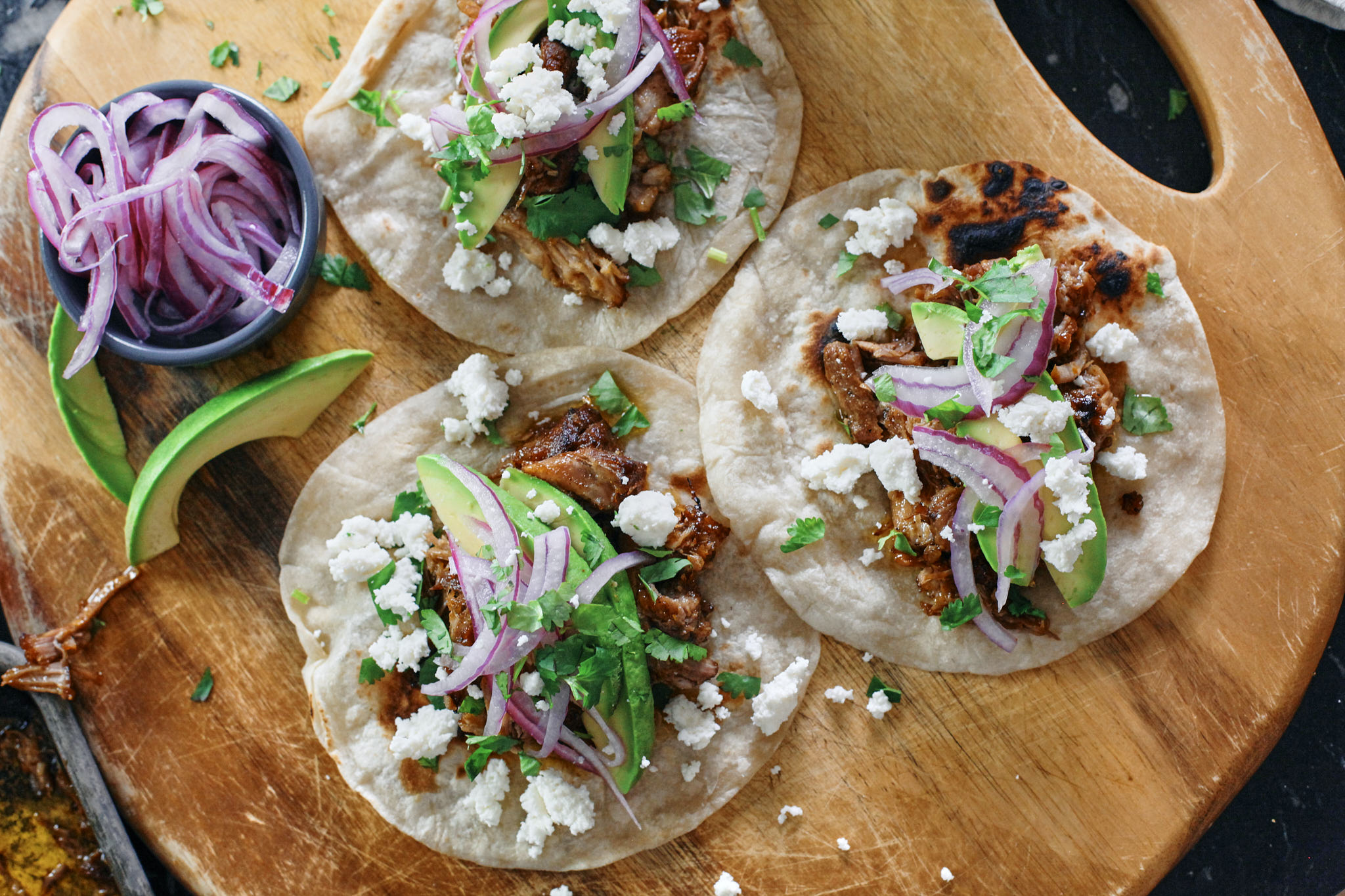 citrus braised pulled pork tacos with avocado, pickled onions, cilantro, queso fresco