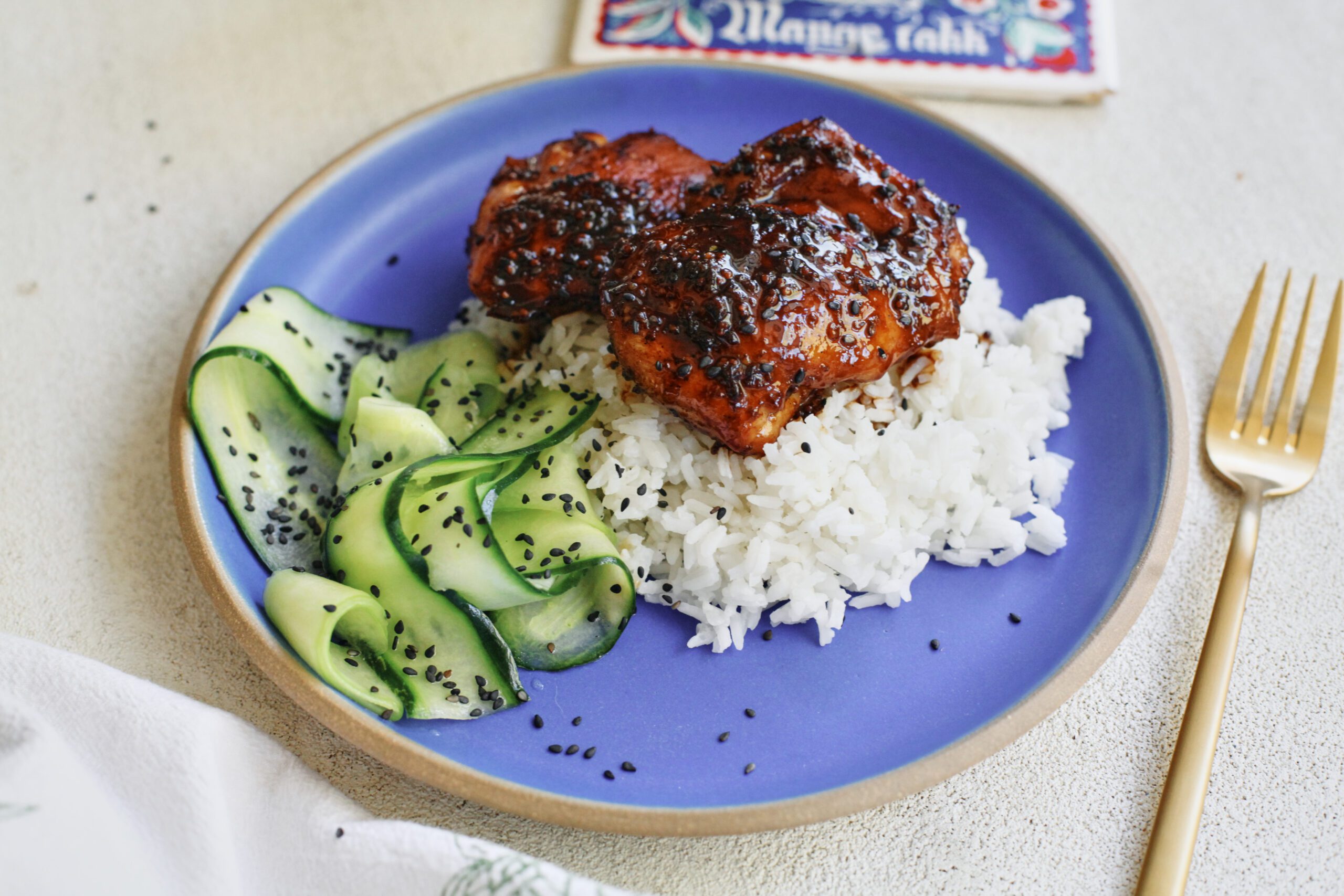 sticky sesame dijon chicken over rice with a cucumber salad