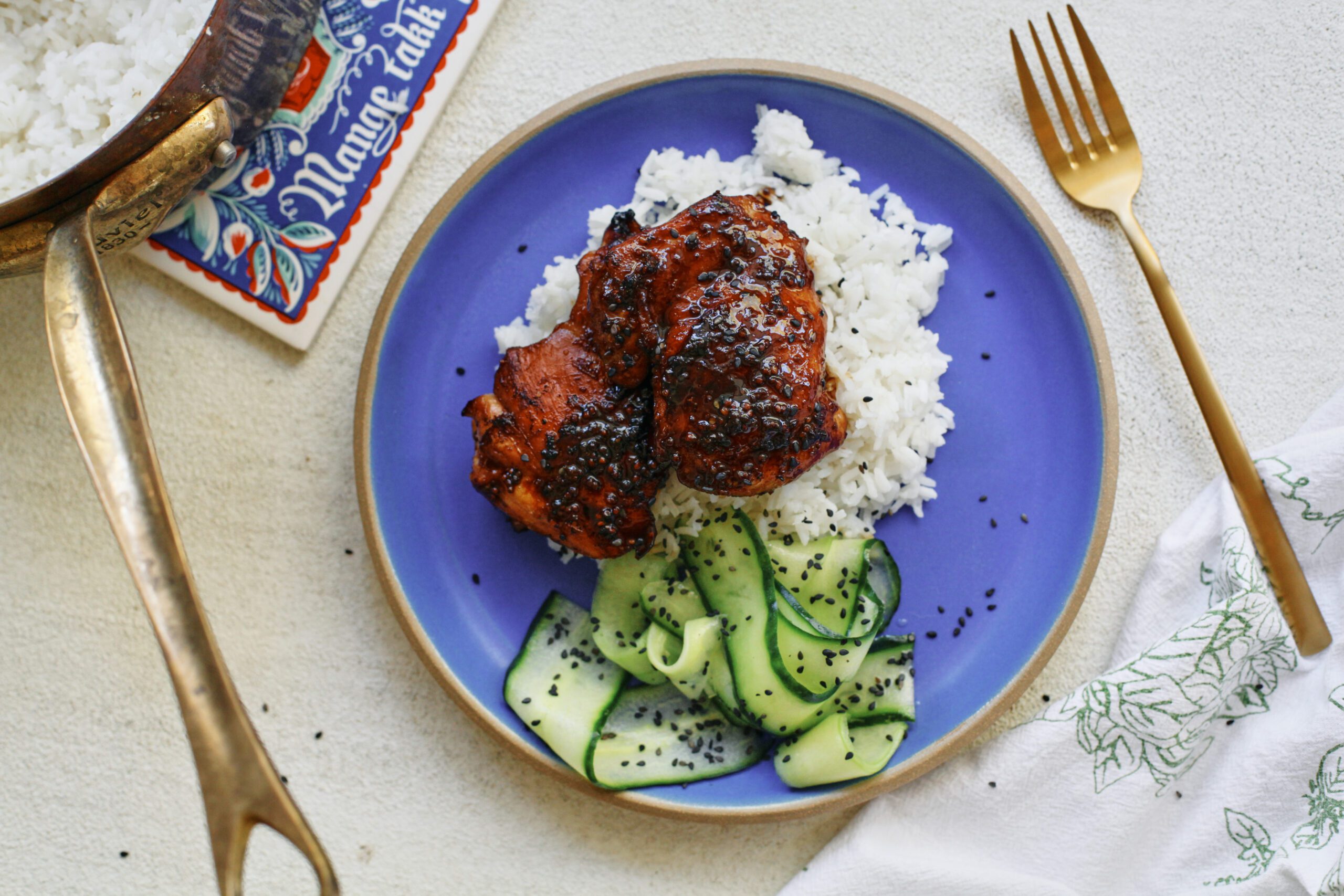 sticky sesame dijon chicken over rice with a cucumber salad