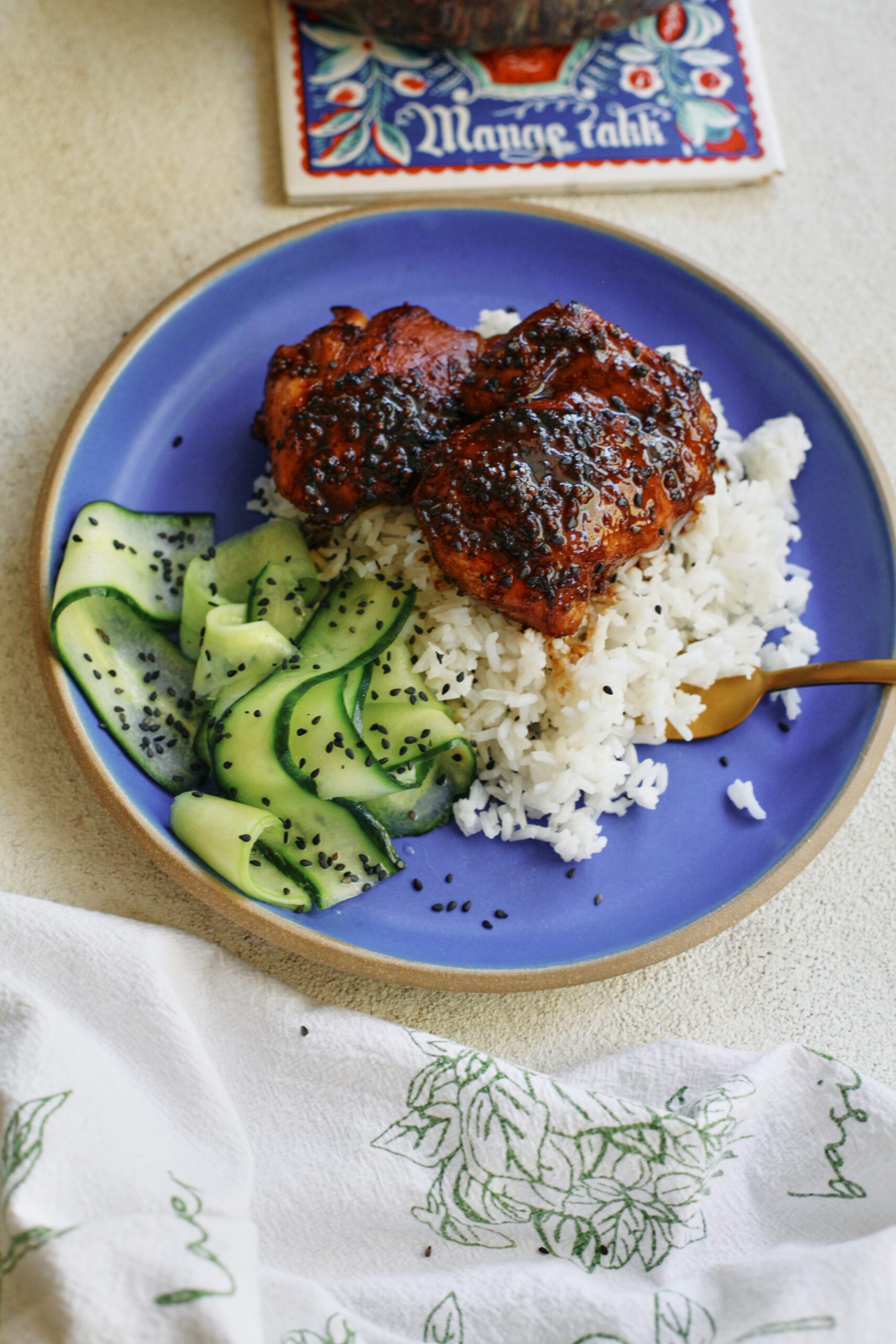 sticky sesame dijon chicken over rice with a cucumber salad