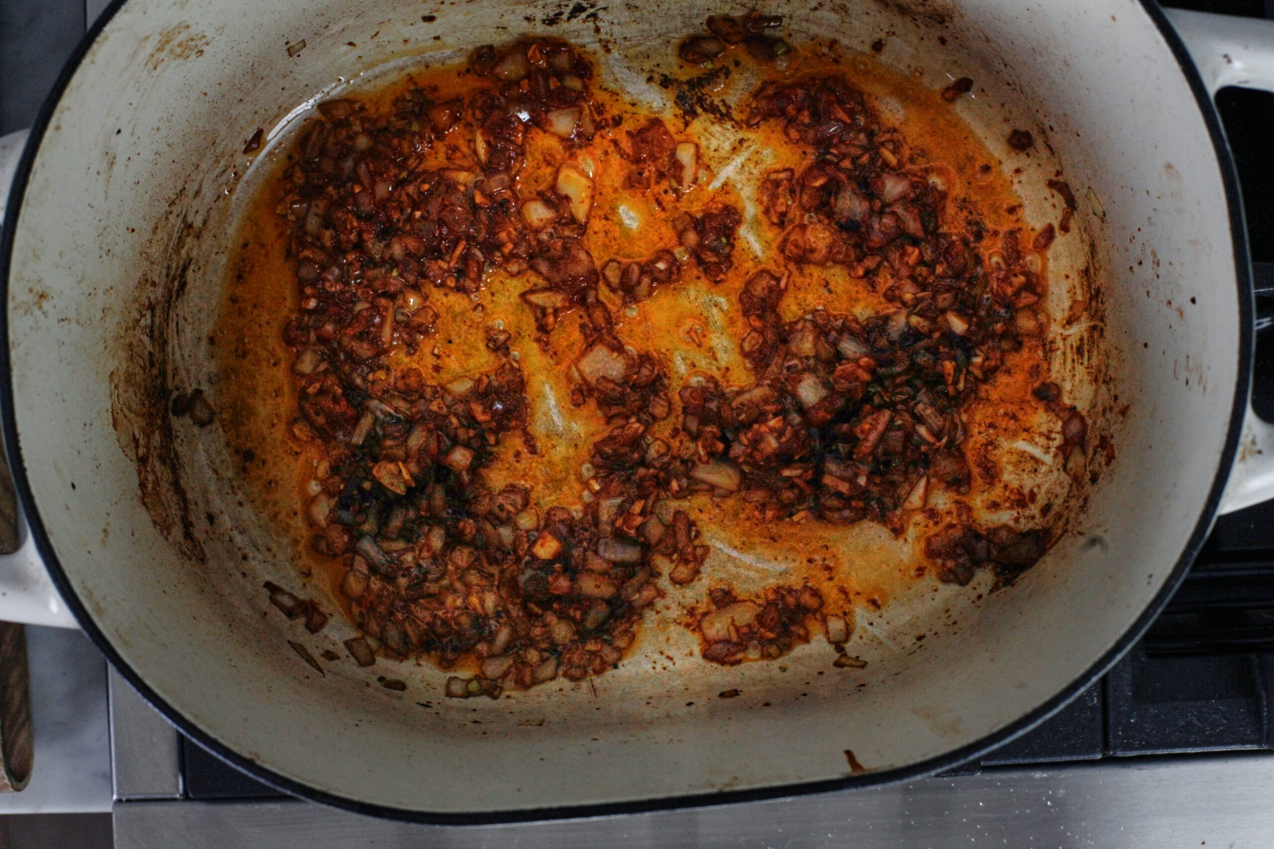 onion, garlic, and tomato paste cooking in the dutch oven