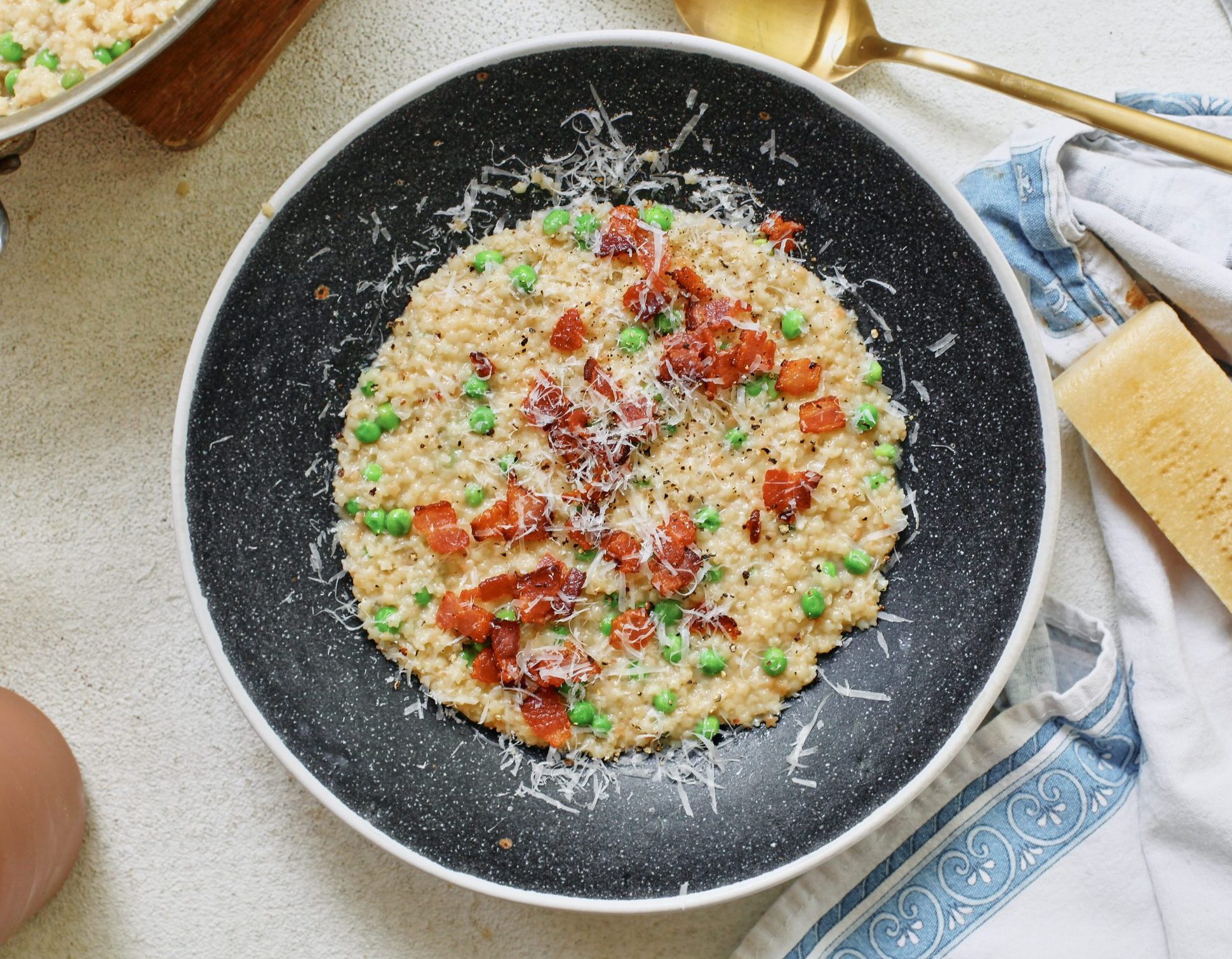 cheesy bacon pastina with peas, served in a black bowl