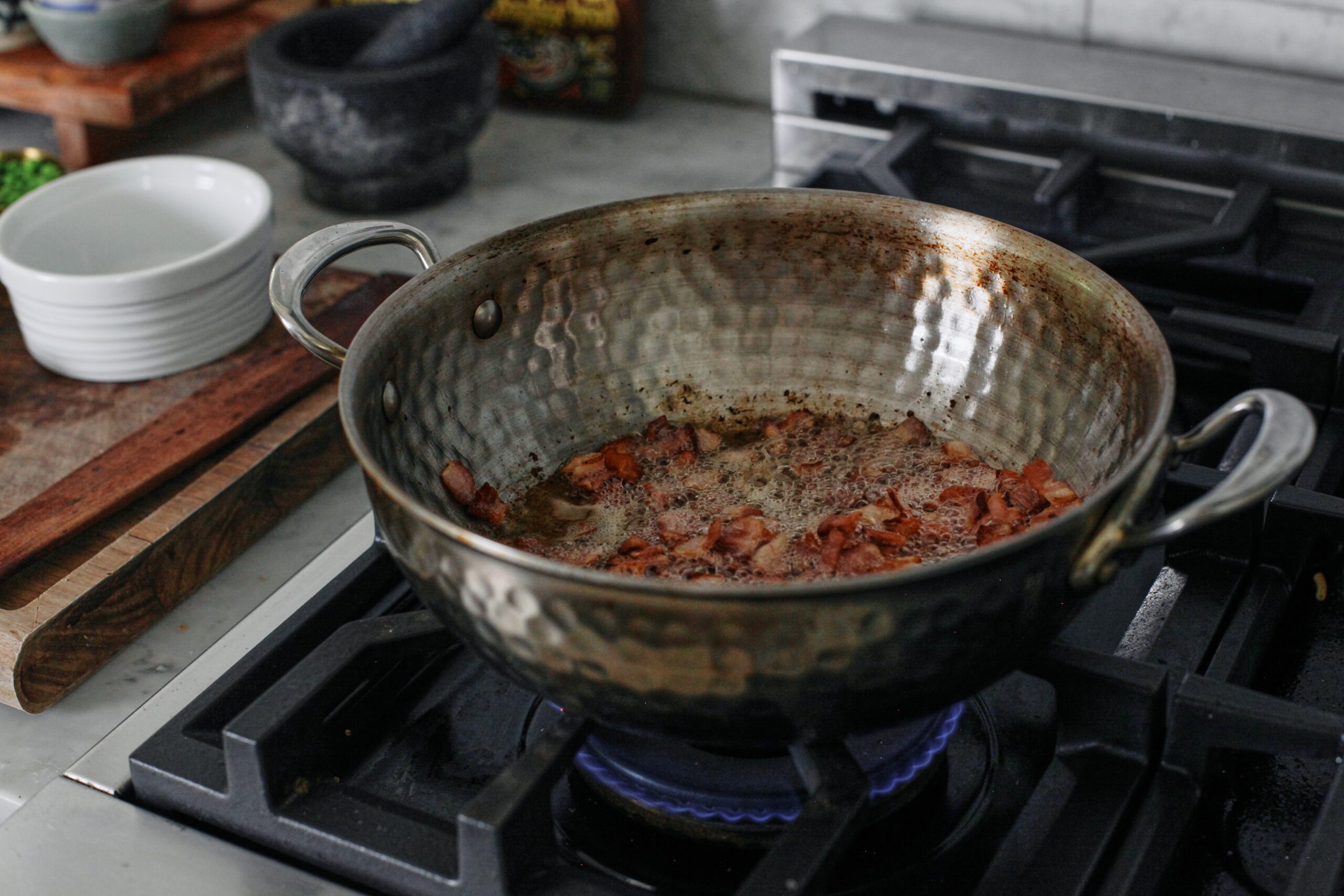 bacon browning in a pan over the stove