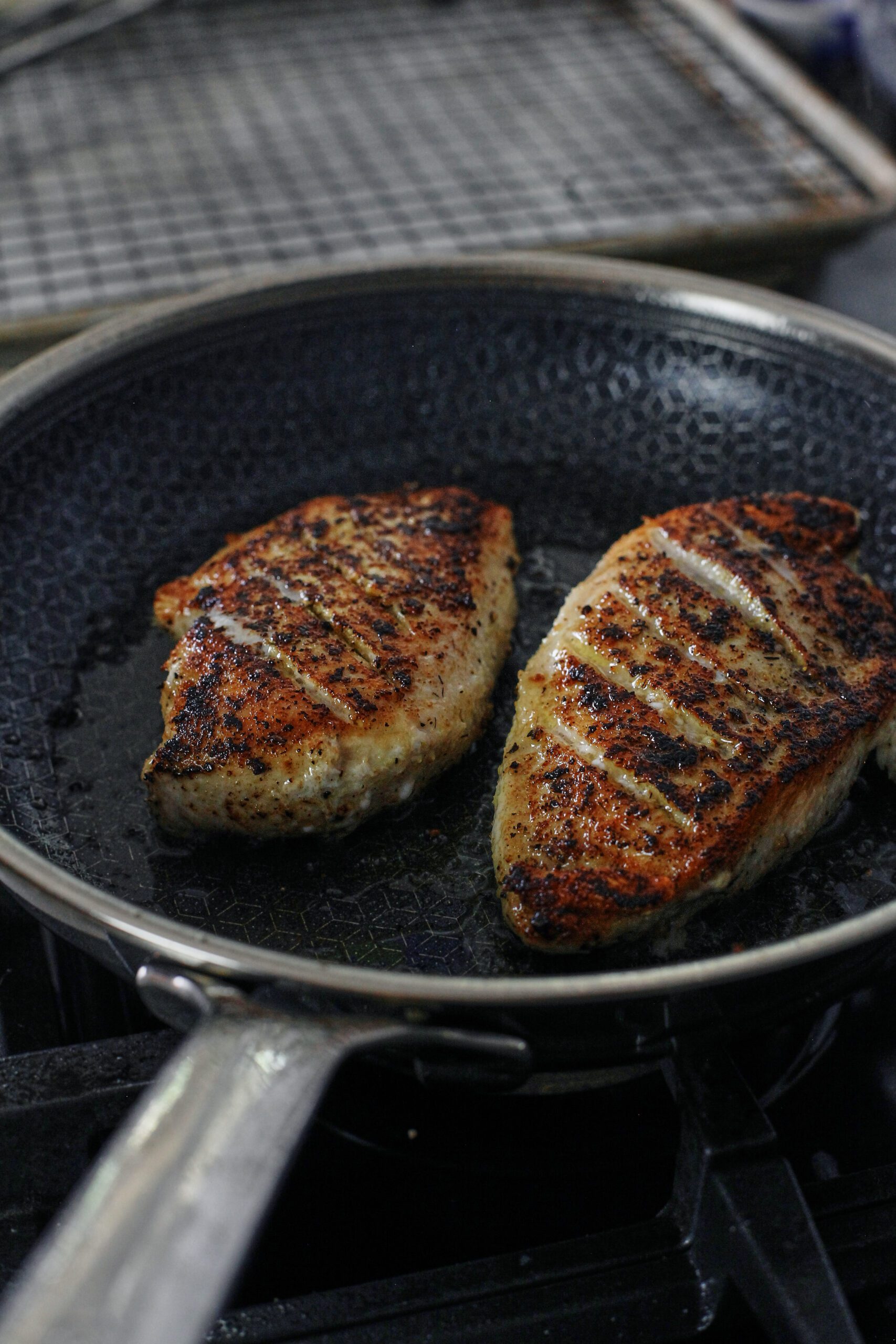 seasoned chicken breasts searing in the pan