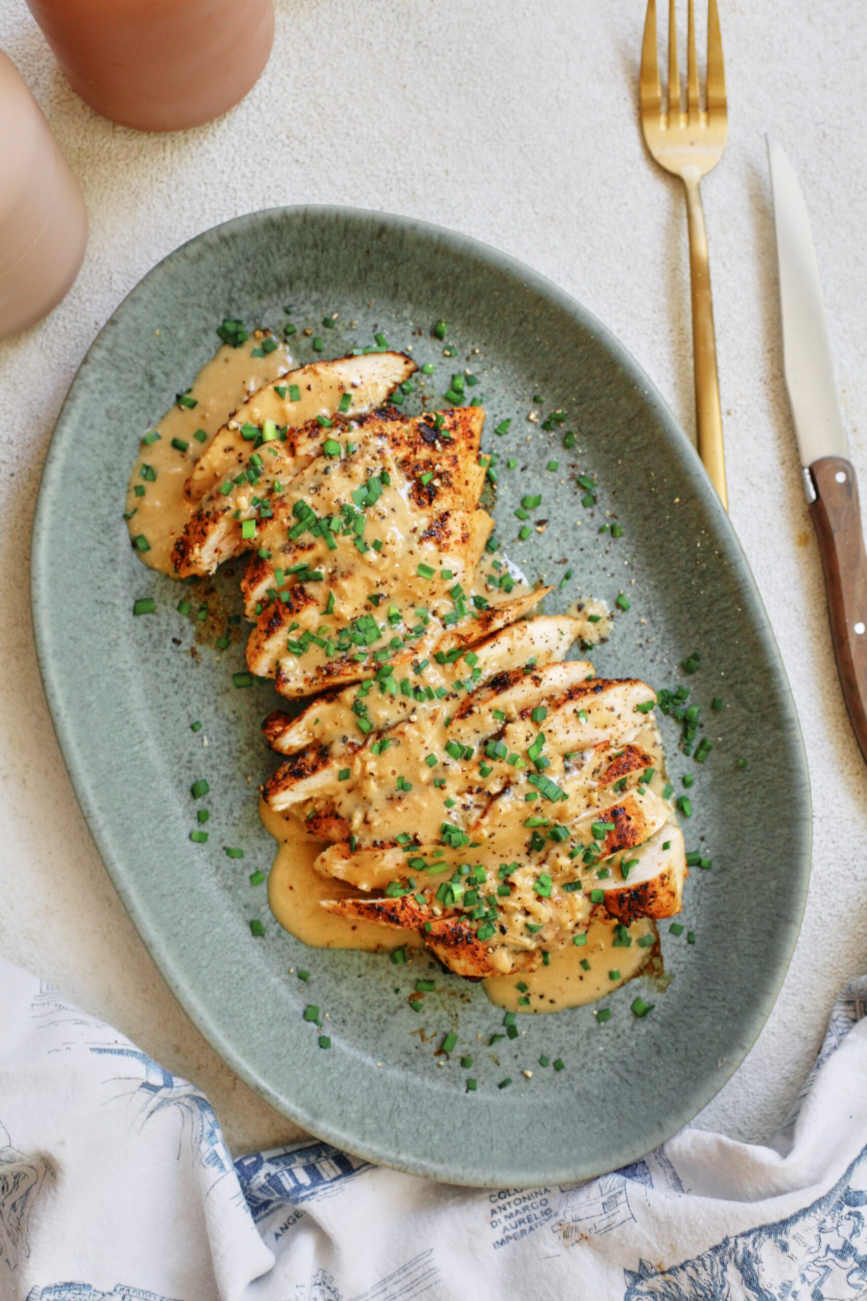 sliced chicken breast with the garlic shallot cream sauce poured on top finished with chives