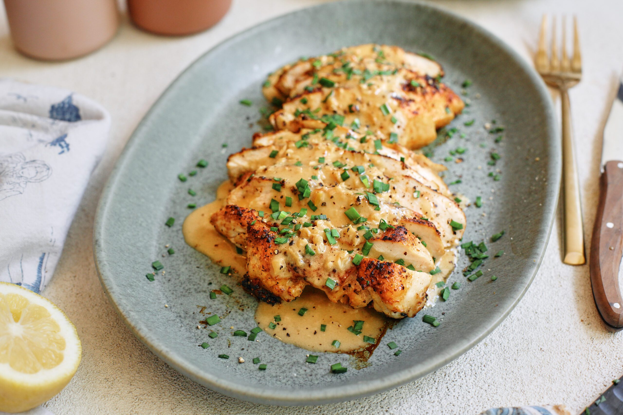 sliced chicken breast with the garlic shallot cream sauce poured on top finished with chives