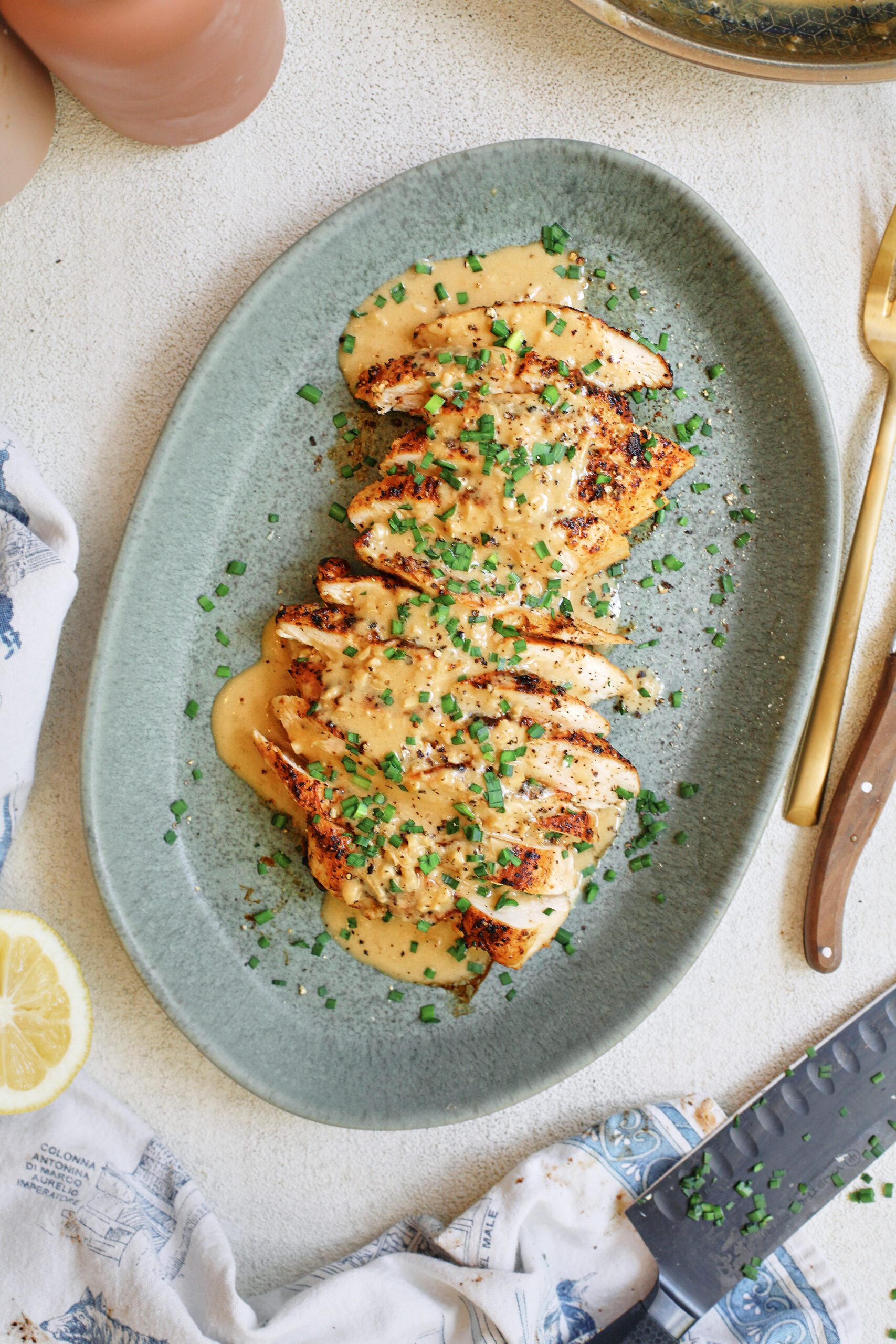 sliced chicken breast with the garlic shallot cream sauce poured on top finished with chives