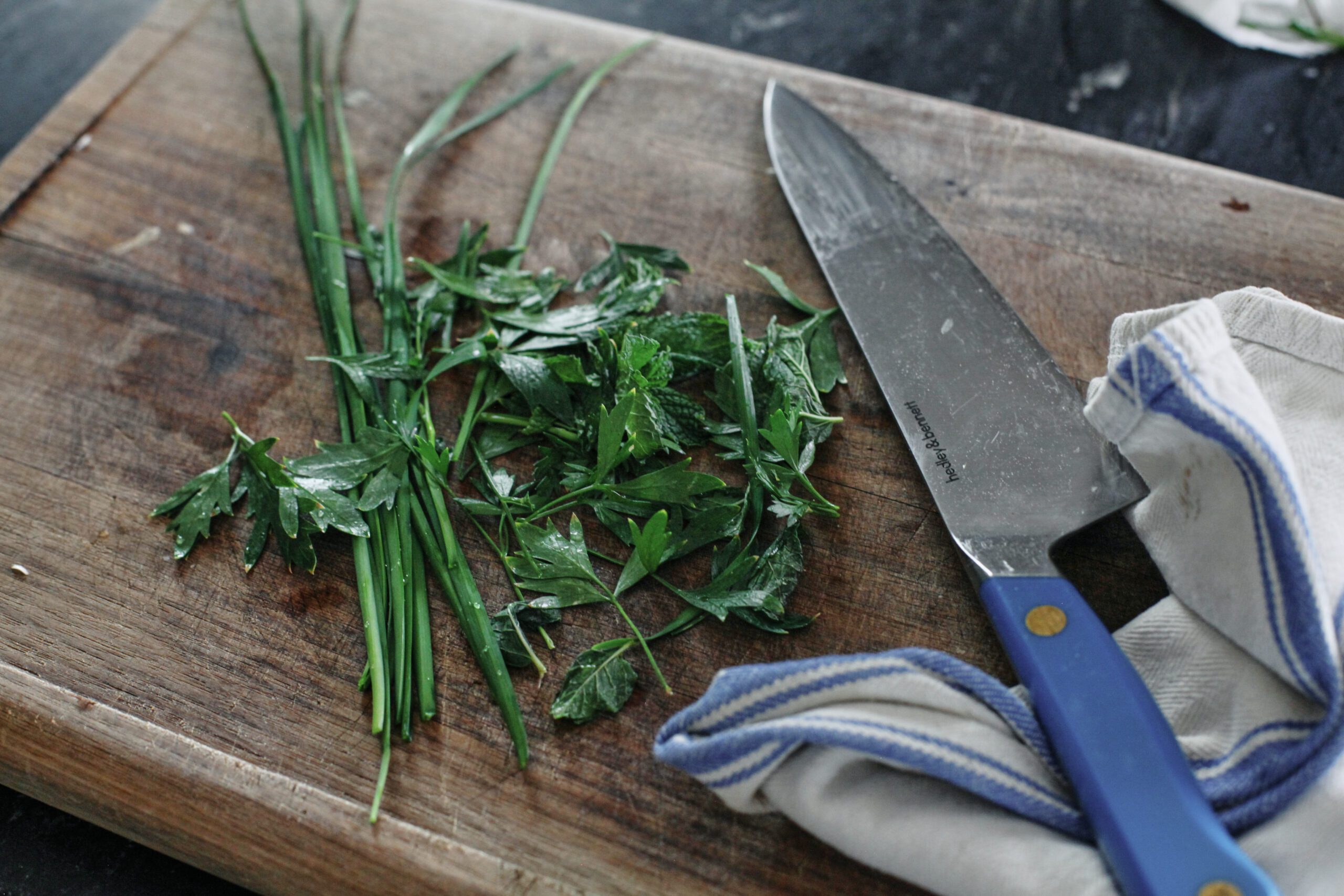 fresh herbs on a wooden cutting board with a knife