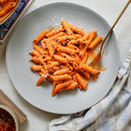 chili oil penne alla vodka on a plate with a gold fork