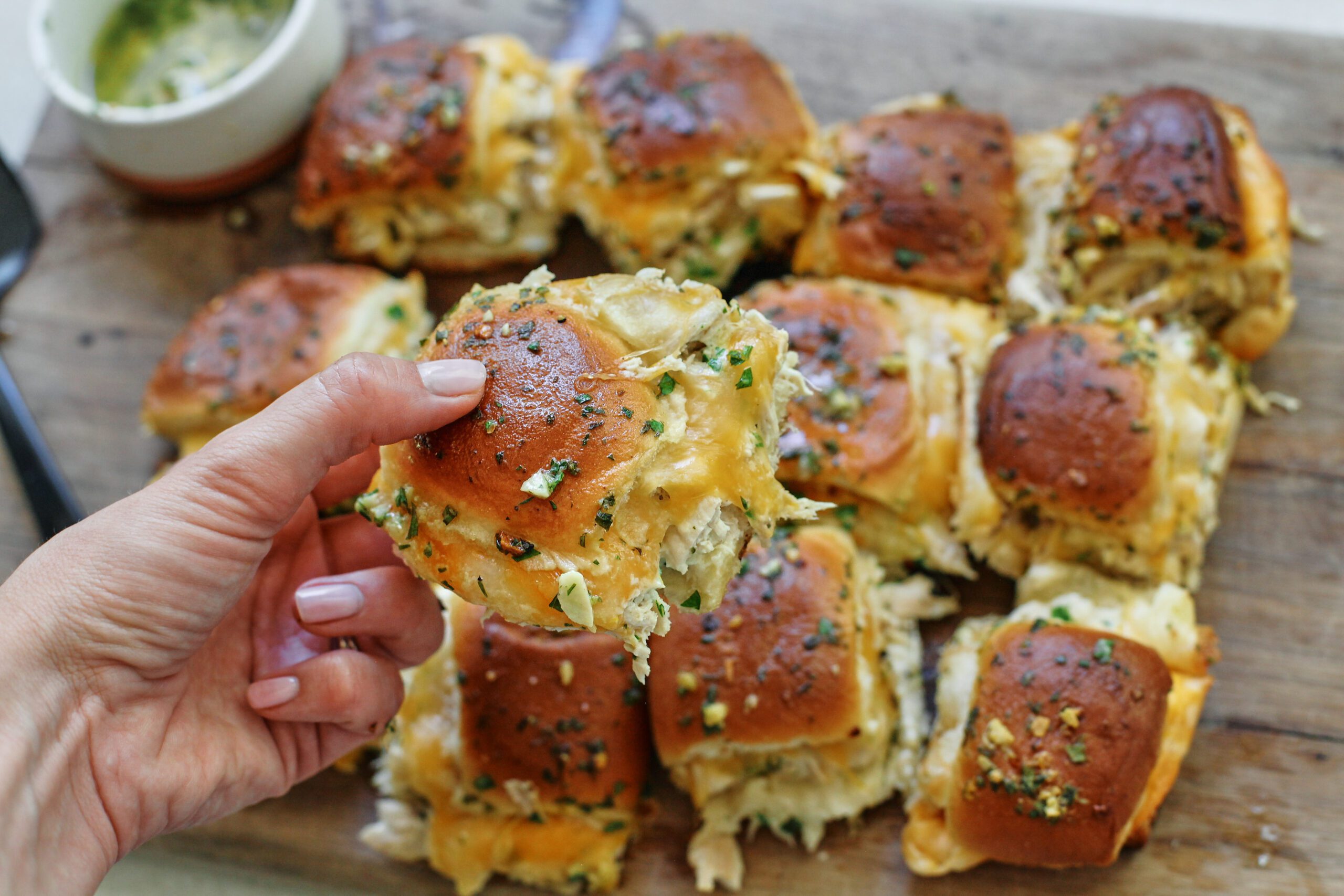 a hand holding one shredded chicken slider
