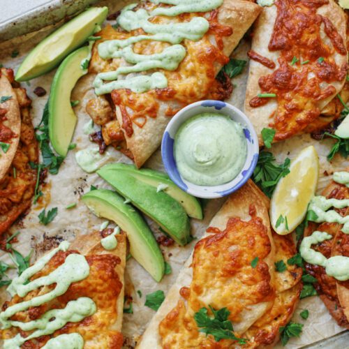 crispy chicken sheet pan tacos with a green goddess ranch on a baking tray - garnished with avocado and lemon