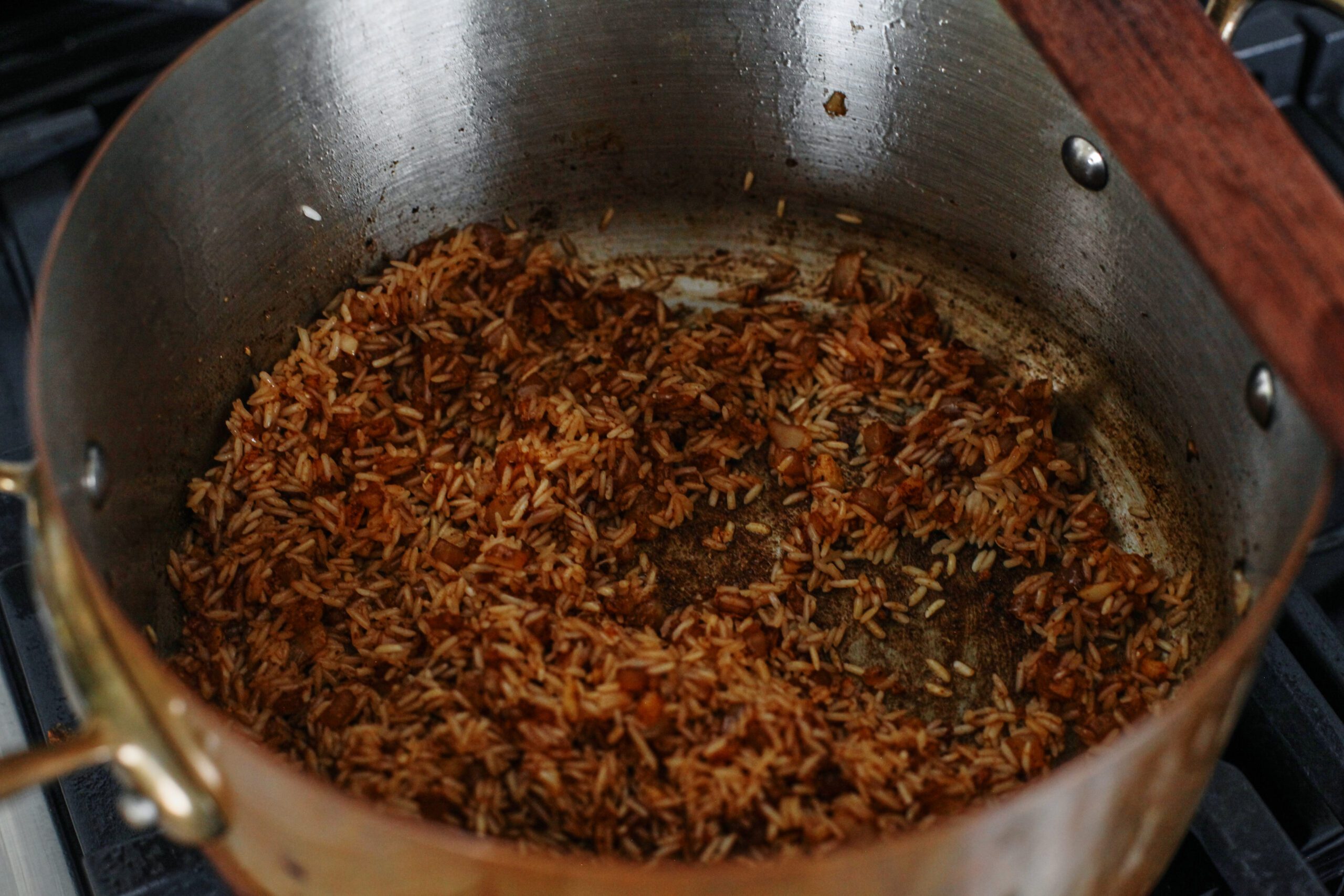 rice toasting in a pot with aromatics
