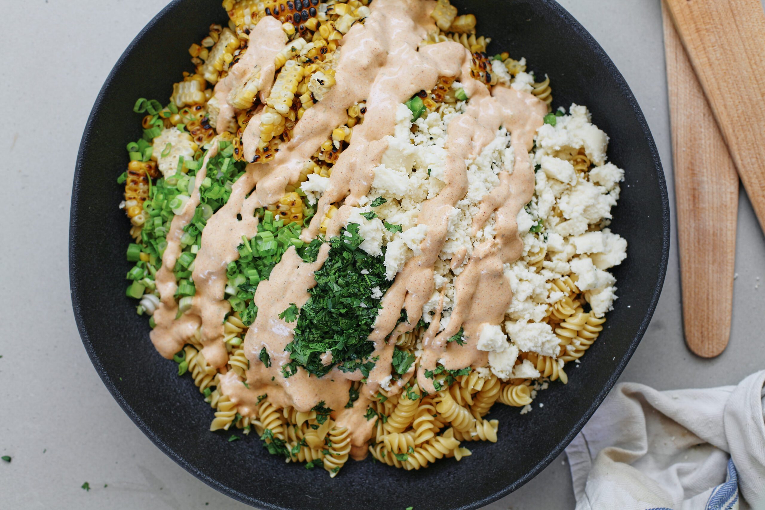elote pasta salad with dressing before being mixed to combine