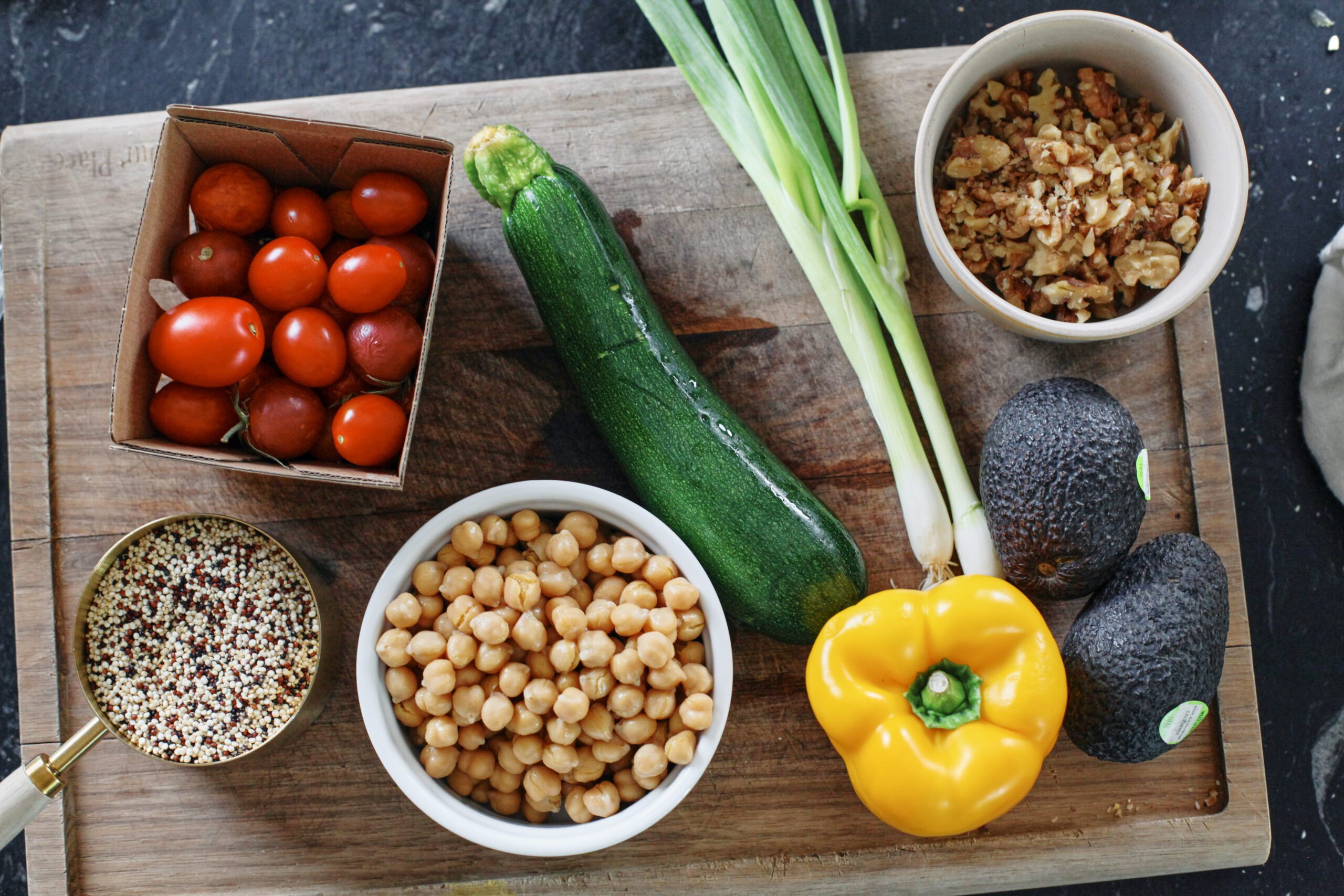 ingredients for high protein grain bowl: quinoa, cherry tomatoes, chickpeas, zucchini, green onions, yellow bell pepper, avocado, chopped California walnuts