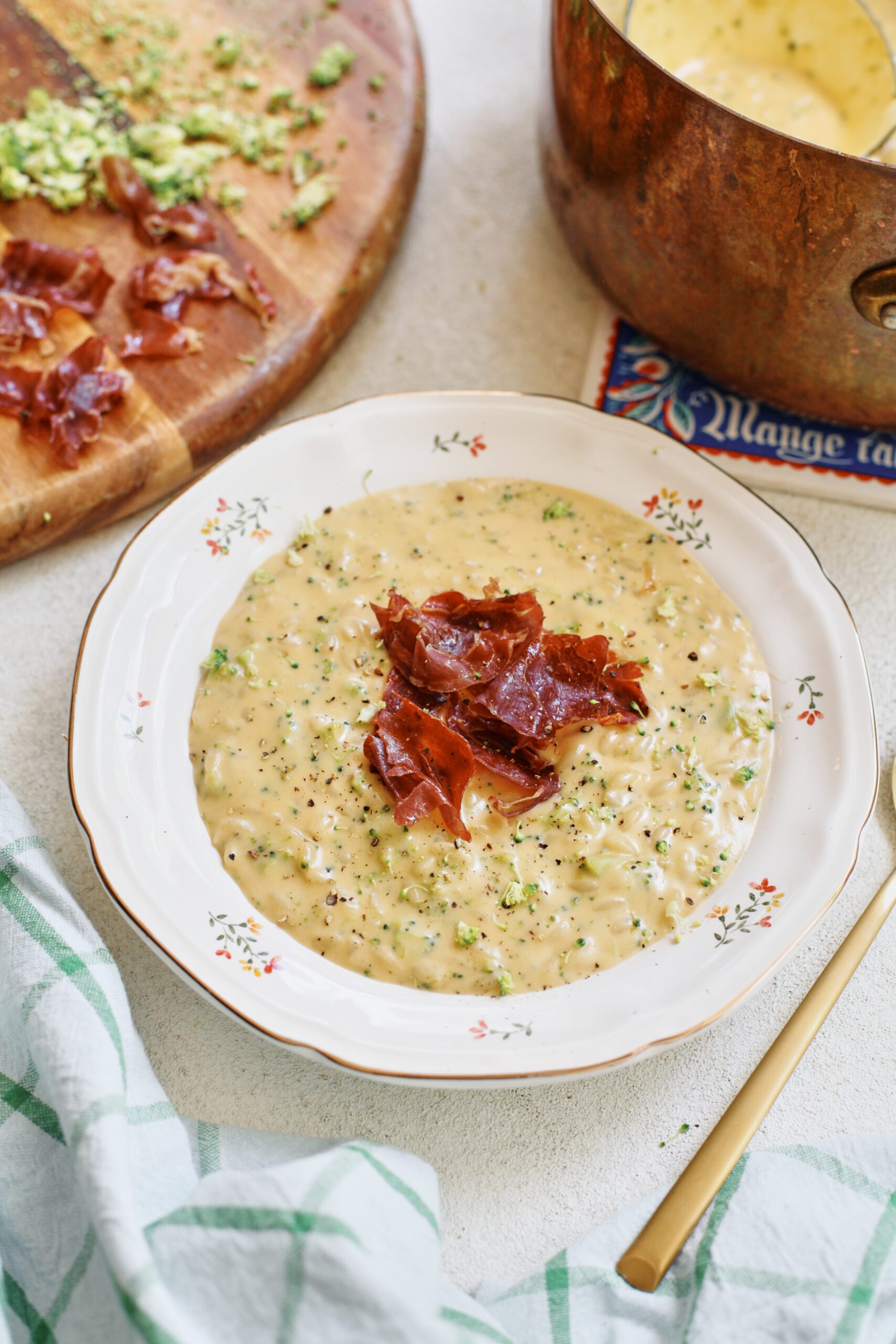 creamy broccoli cheddar orzo soup with crispy pancetta on top in a bowl
