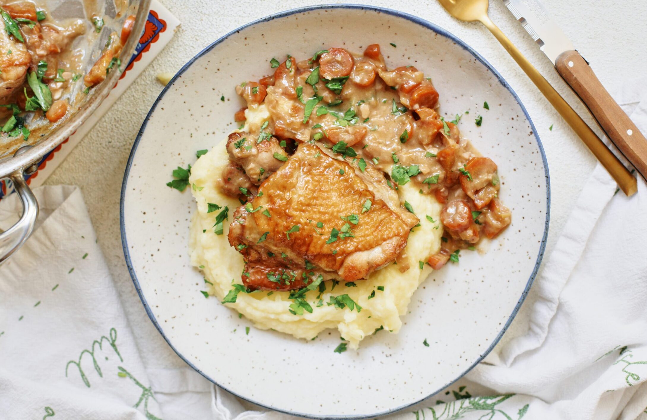 plated coq au vin blanc over a bed of creamy mashed potatoes with fresh Italian parsley on top