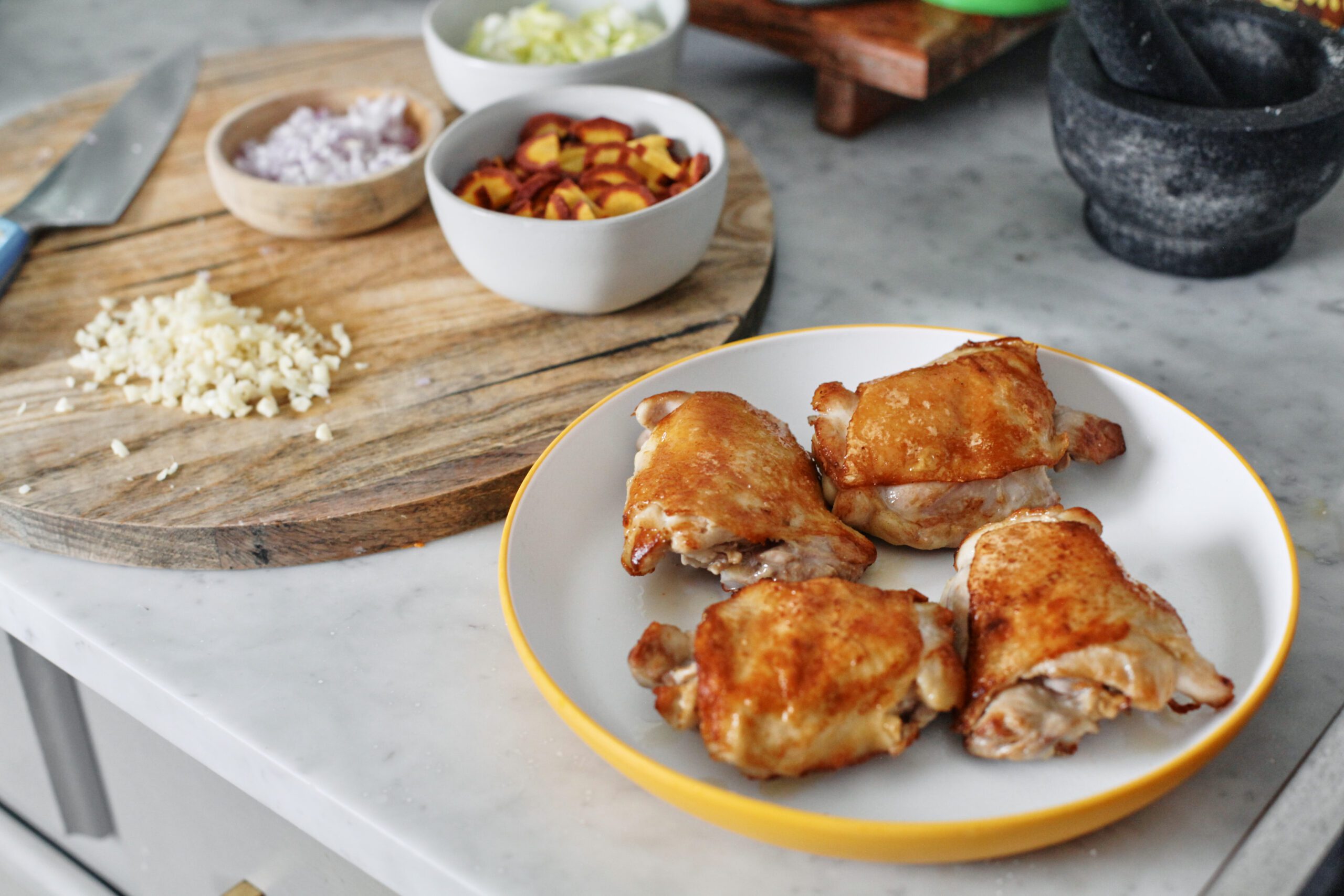 Coq au Vin Blanc 2 perfectly golden seared chicken thighs next to the mise en place ingredients about to go into the sillet