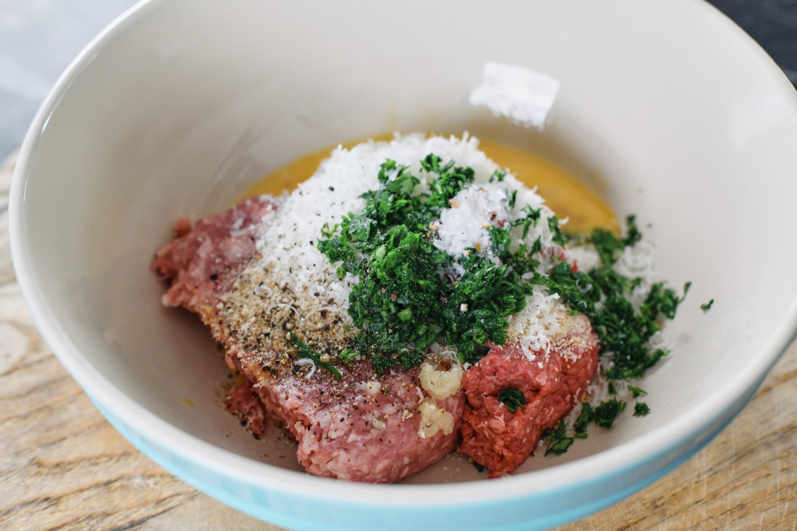 meatballs before being mixed together: ground beef and pork, beaten egg, parmesan cheese, chopped parsley