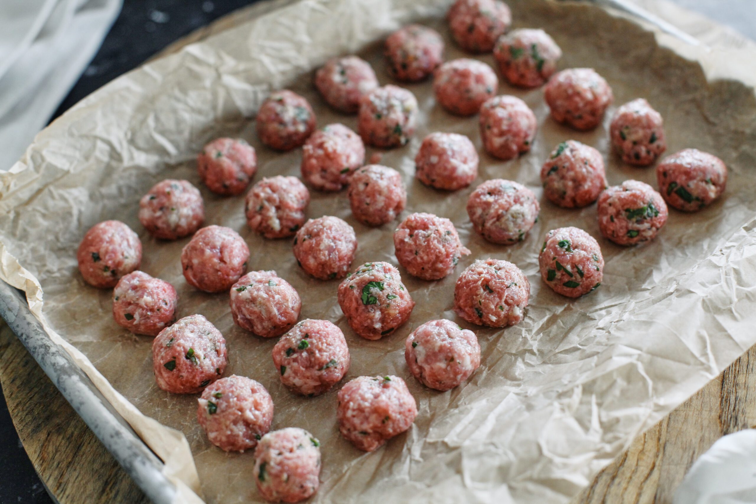small meatballs arranged on a lined baking sheet