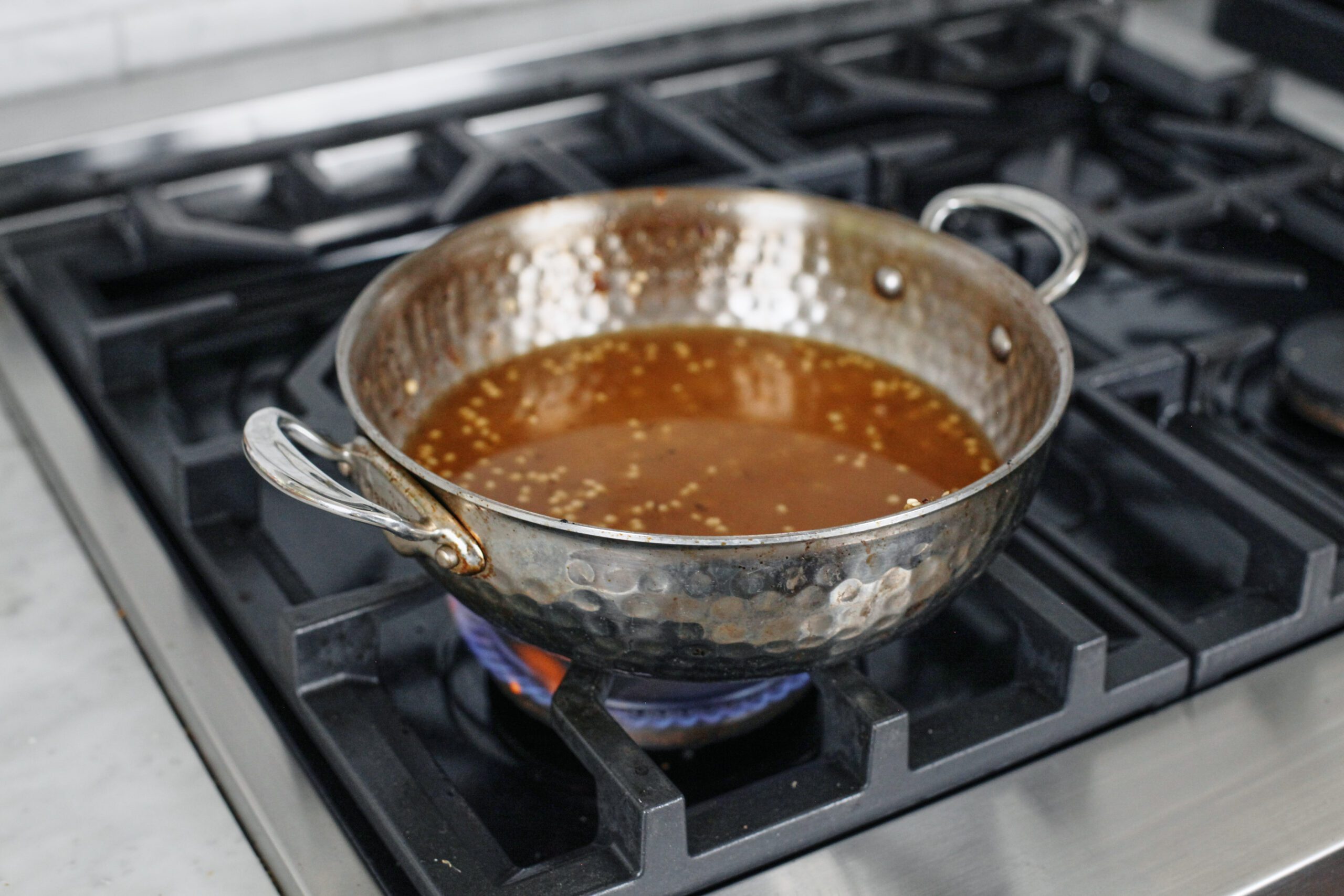 pearl couscous and chicken broth in a pan ready to be cooked