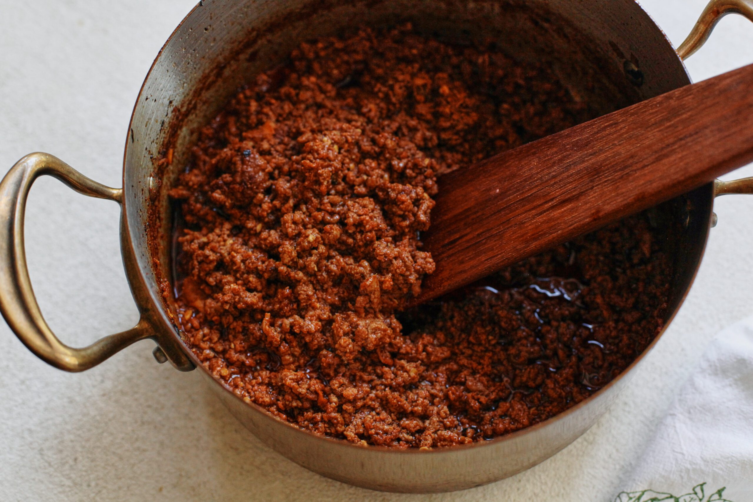 texas style chili being stirred with a wooden spoon