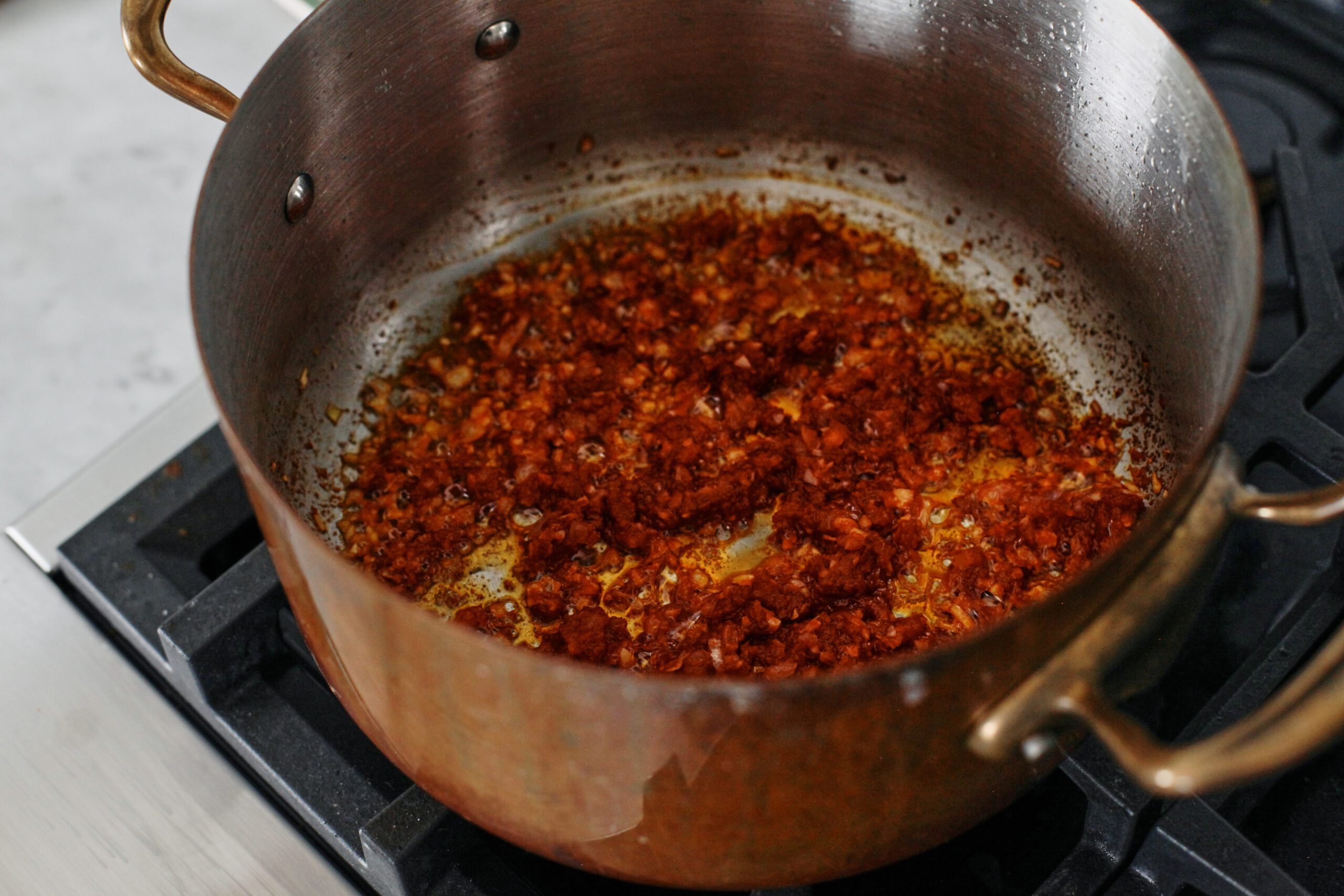 tomato paste sautéing with chopped onion and garlic in a large pot