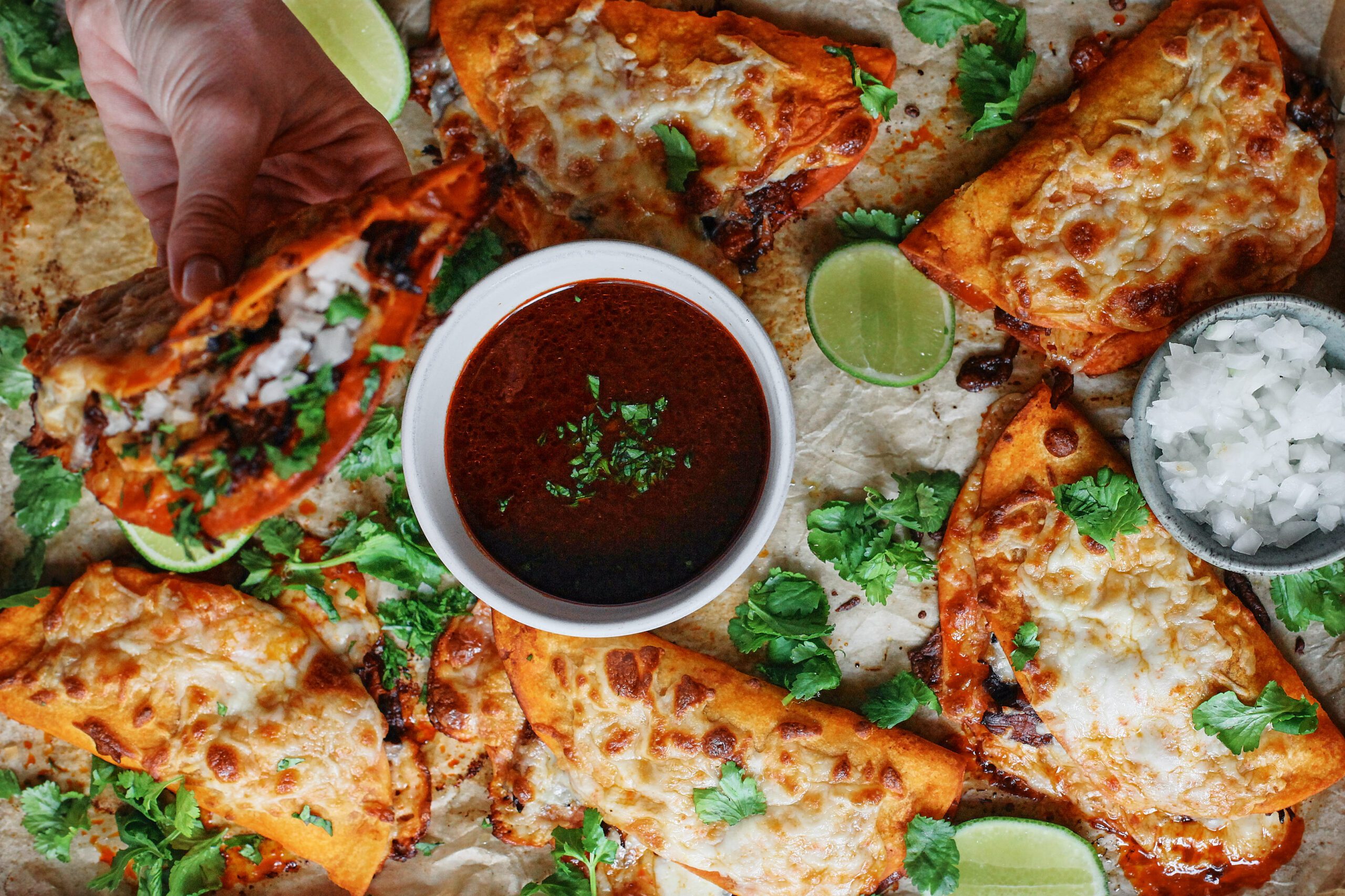 birria sheet pan tacos + a bowl of consomme dressed with cilantro, lime wedges, and a bowl of chopped white onions