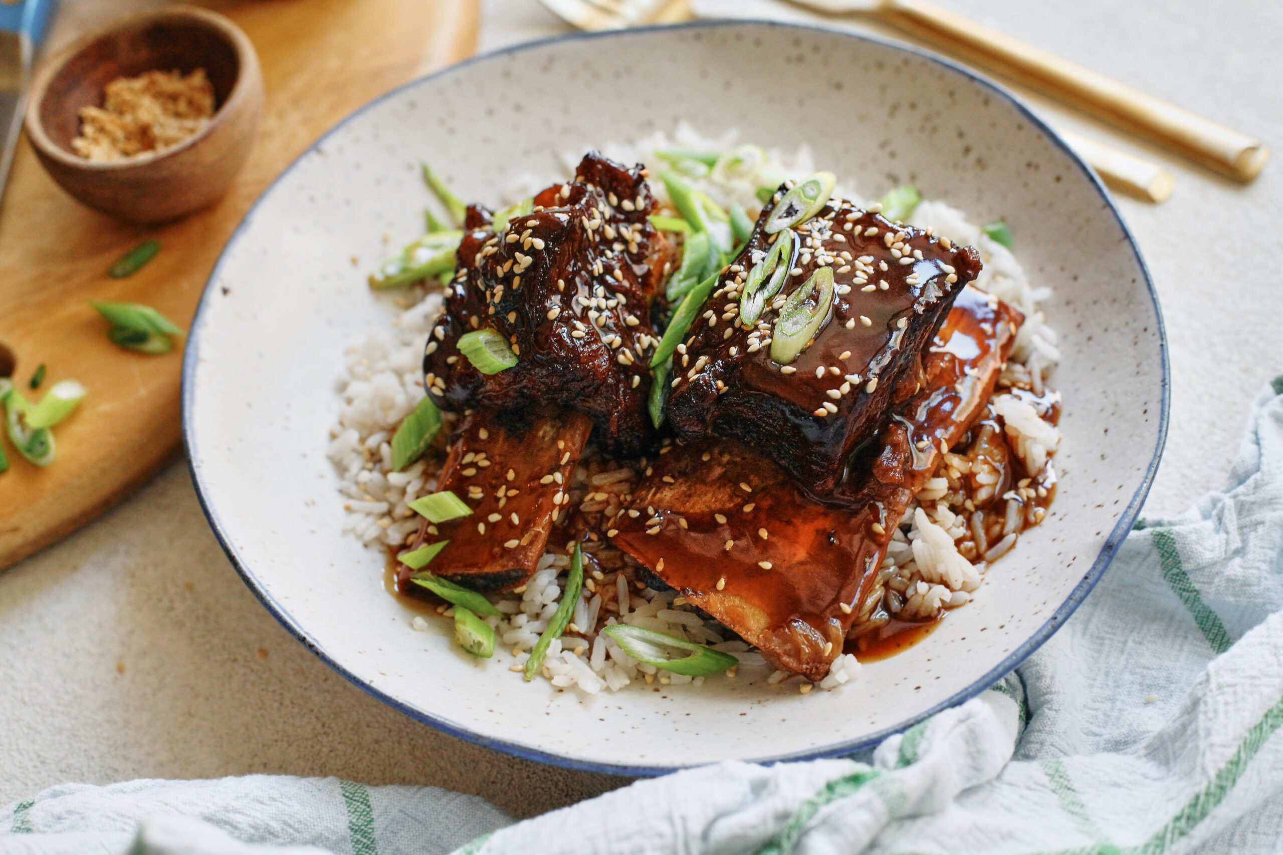 sticky soy and citrus short ribs over white rice, garnished with green onions and sesame seeds