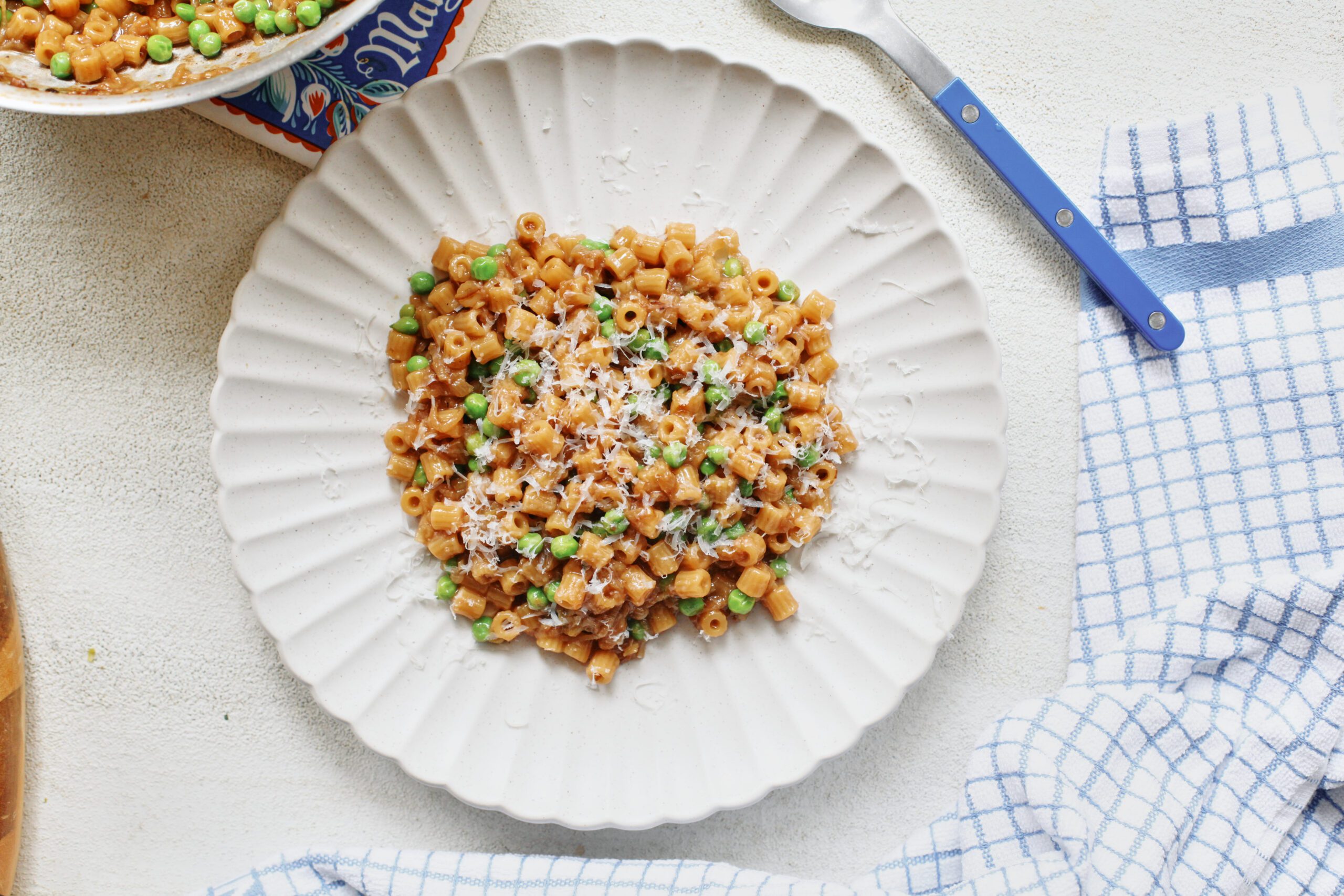 overhead photo of caramelized shallot ditalini with peas on a white plate